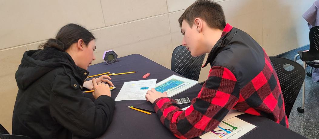 Two students sitting at table looking at papers