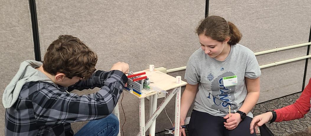 Two students sitting on floor working on wind turbine