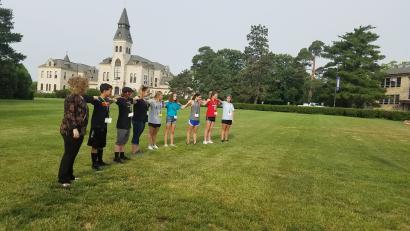 students standing a long line hands on each others shoulders representing wind turbine blade