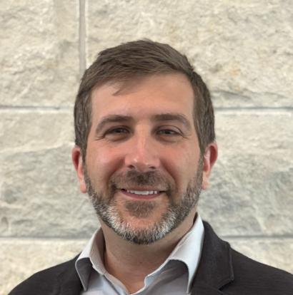 Man wearing dress shirt and jacket in front of limestone wall (2025)