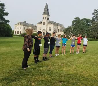 students standing a long line hands on each others shoulders representing wind turbine blade